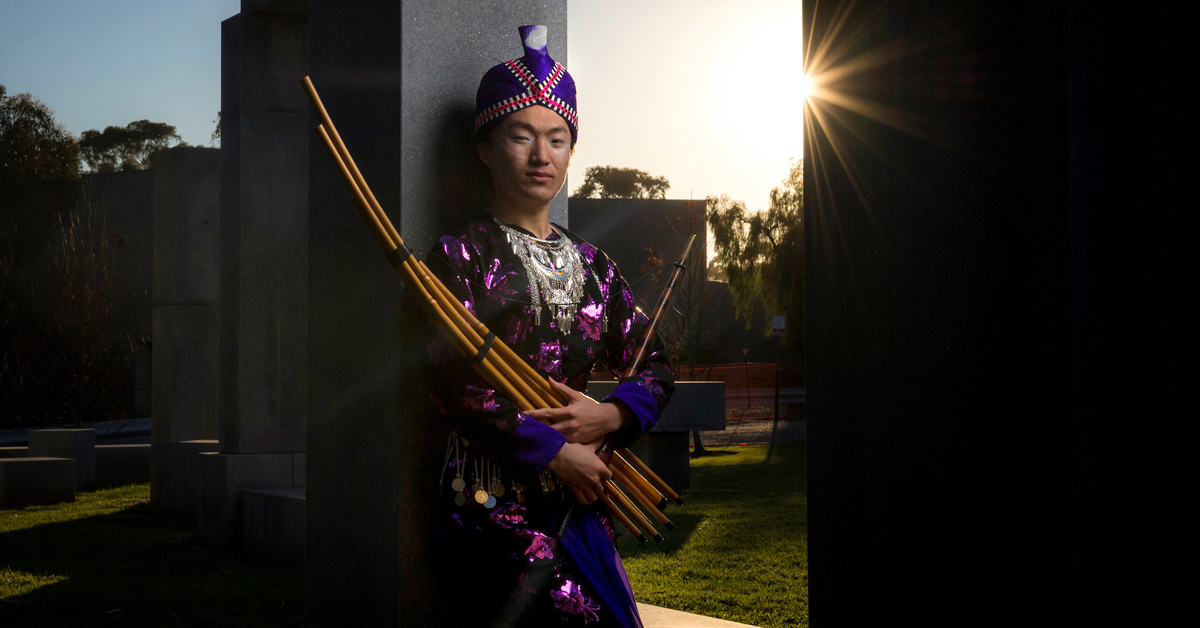 UC San Diego senior Eugene Tsim Nuj Vang poses in traditional Hmong clothing to honor their heritage. They also hold a cherished instrument of their grandfather's called a qeej, a type of mouth organ made from bamboo pipes that has a 3,000-year history. Photos by Erik Jepsen/University Communications.